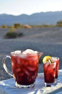 Pitcher and drink glasses of hibiscus flower iced tea in mojave desert setting