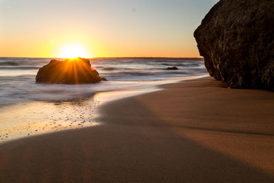 Scenic view of beach against clear sky during sunset