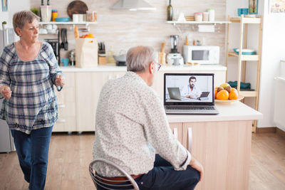 Rear view of man using mobile phone at home