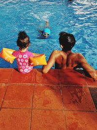 Rear view of father with children in swimming pool