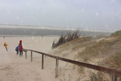 People at beach against sky during storm