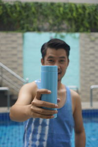 Portrait of man drinking glass in swimming pool