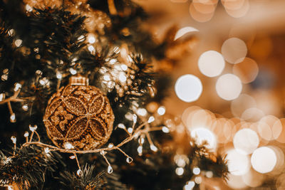 Christmas tree green branches decorated with golden artistic christmas ball and bokeh magic garland