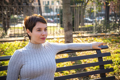 The young woman is sitting on a park bench in rome. 