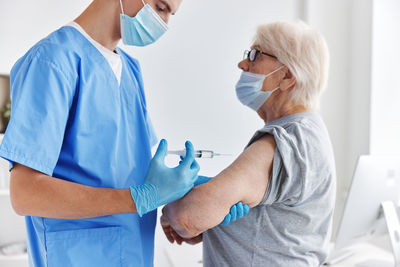 Doctor wearing mask vaccinating patient at hospital