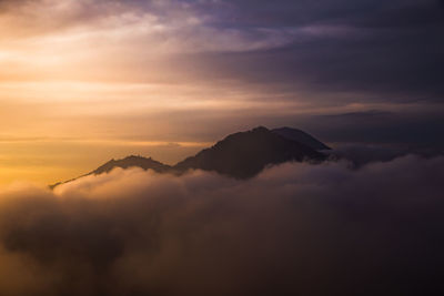 Scenic view of clouds and mountains against sky during sunset