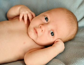 Close-up portrait of baby lying on bed at home
