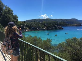 People standing by railing against blue sky