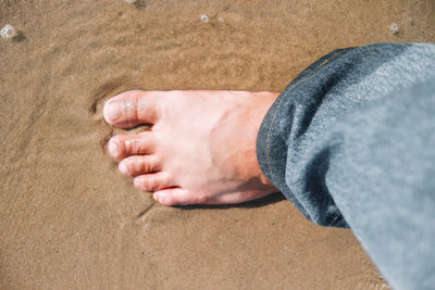 Low section of man relaxing on sand