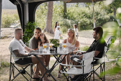 Friends with children relaxing under garden gazebo