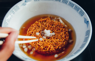 Close-up of hand holding soup in plate