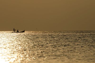 Silhouette boat sailing on sea against clear sky during sunset