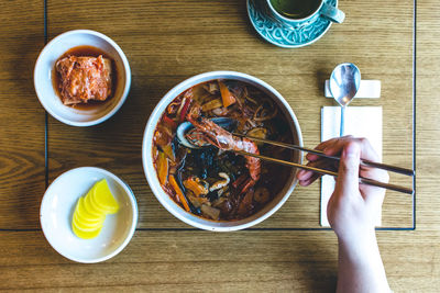 Cropped hands of person eating food on table