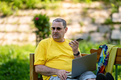 Portrait of young man using laptop while sitting at park