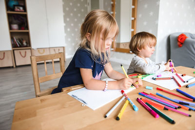 Little boy with sister drawing with felt-tip pens