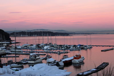 Boats moored in lake against sky during sunset