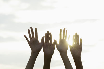 Cropped hands of people against sky