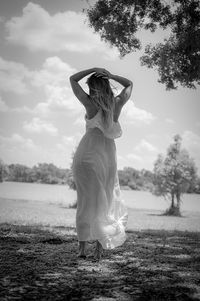 Rear view of woman standing on field against sky