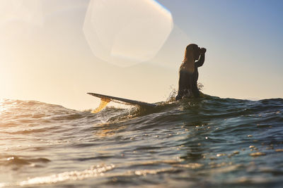 Man on surfboard shielding eyes in sea during vacation