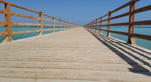 Pier over sea against clear sky on sunny day