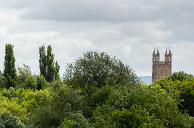 View of trees and buildings against cloudy sky