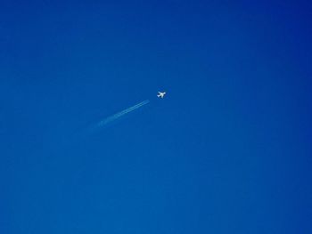 Low angle view of airplane flying against clear blue sky