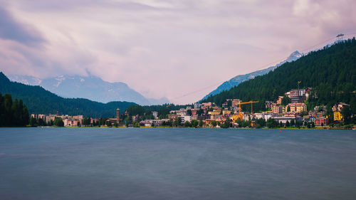 Scenic view of lake by buildings in city against sky