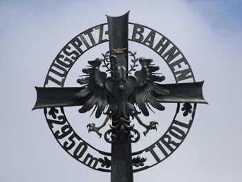 Low angle view of cross sculpture against sky