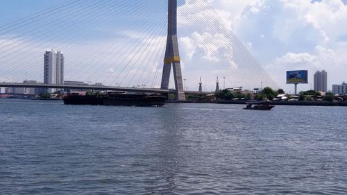 Bridge over river against cloudy sky