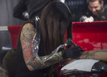Female artist making tattoo on customer hand