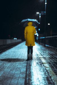 Rear view of man standing on wet street