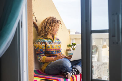 Mature woman using laptop while sitting by window