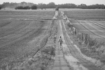 Rear view of woman walking on field