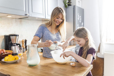 Mother and daughter preparing pancakes in kitchen
