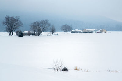Scenic view of snow covered field against sky