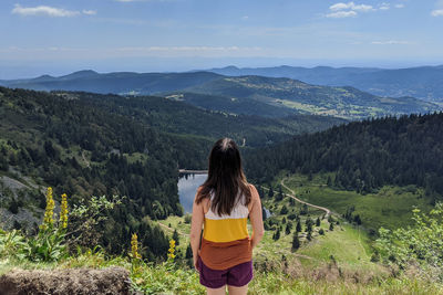 Rear view of woman looking at mountains against sky