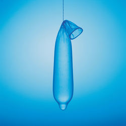 Close-up of condom with water against blue background