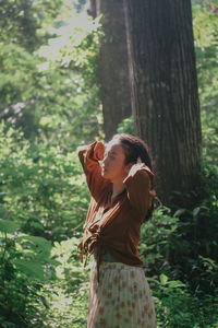 Side view of woman standing against trees