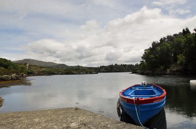 Boat moored on lake against sky