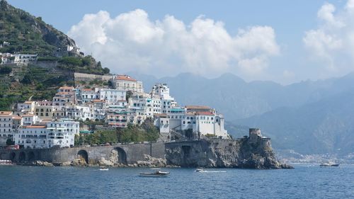 Buildings by sea against sky in city