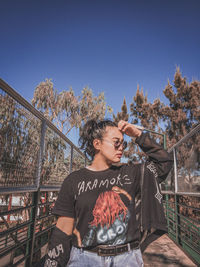 Portrait of young woman standing against clear sky