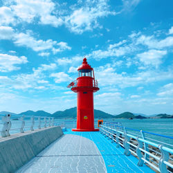 Lighthouse amidst sea and buildings against sky