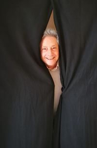 Portrait of a smiling mid adult woman standing against curtain