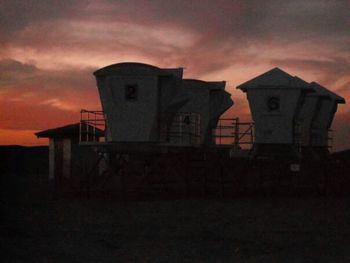 Silhouette of built structure against cloudy sky at sunset