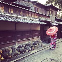 Rear view of woman standing by building