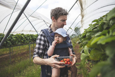 Young man holding ice cream in greenhouse