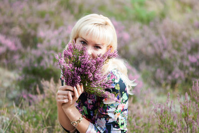 Portrait of woman holding lavender flower at field