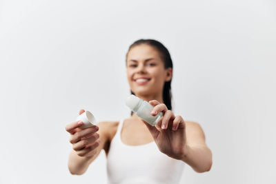 Portrait of smiling young woman gesturing against white background