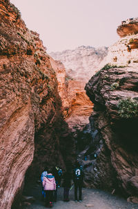 Rear view of people on rock by mountain