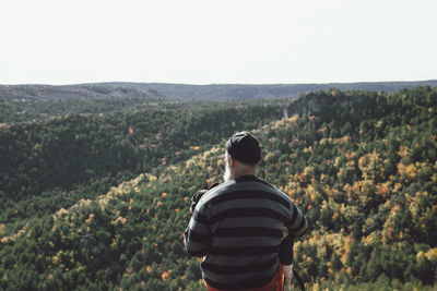 Man sitting on his back with dog on a rock looking at the landscape on the mountain cliff